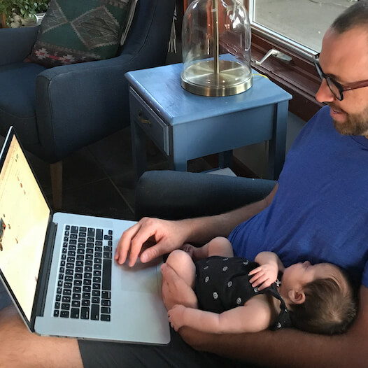 Mark holding a baby while coding